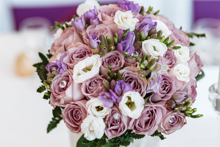A close-up of a floral bouquet delivered by Harrow on the Hill Florist, featuring soft pink and lavender roses, white lisianthus, and purple freesias, arranged in a compact, rounded style with green f