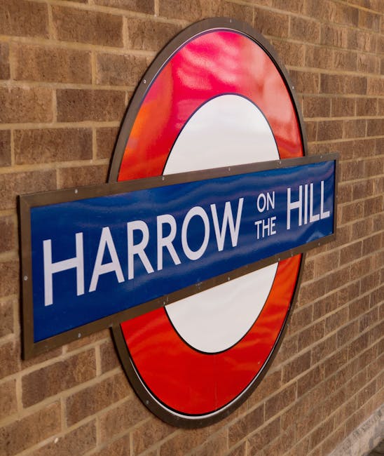 The image features a close-up of a London Underground station sign for Harrow on the Hill, mounted on a brick wall. The sign is circular with a red ring and a central white circle, complemented by a b